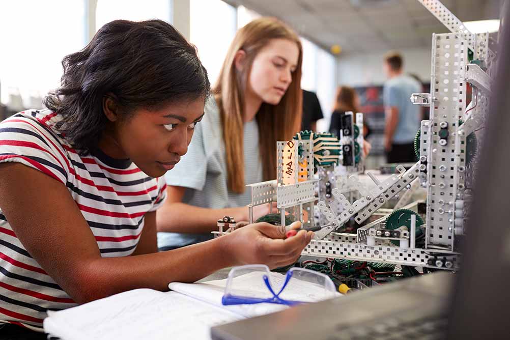 Two female college students building machine in engineering class. 