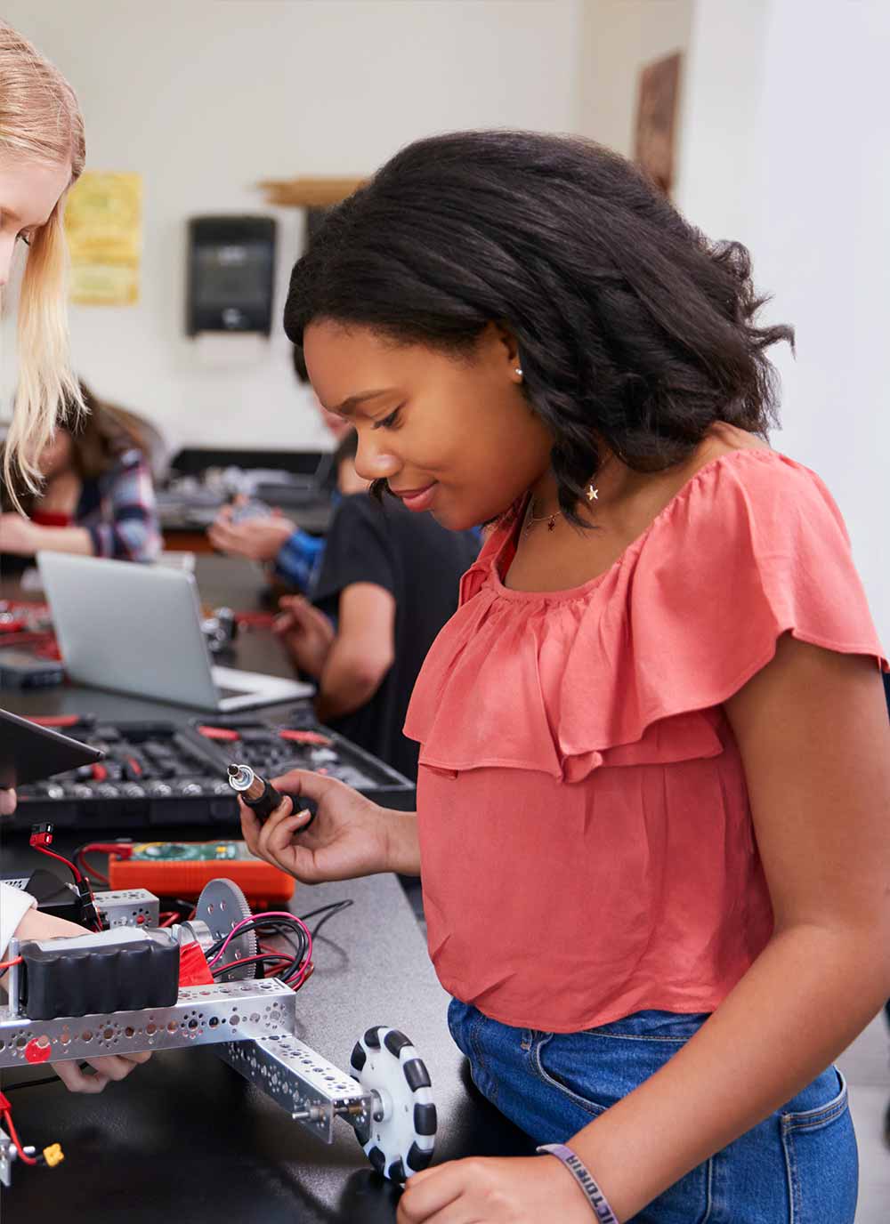 A female student building robotic vehicle in engineering class.