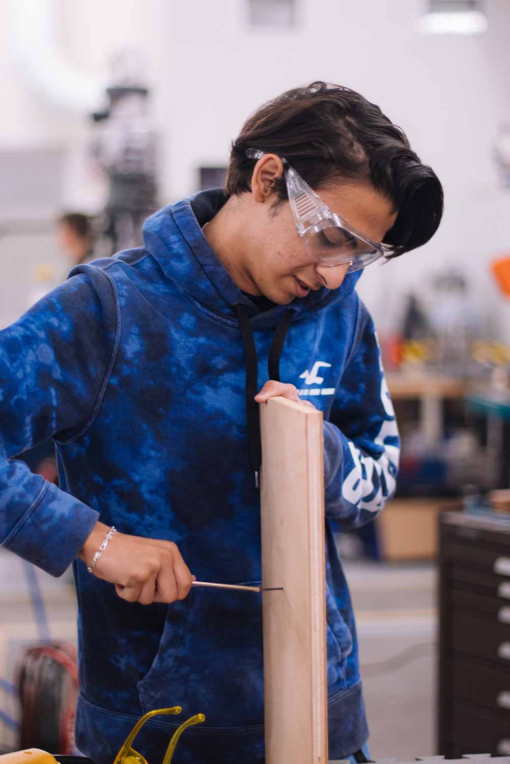 Young male with safety goggles working on project in workshop. Photo by Jeremy Bishop on Unsplash.